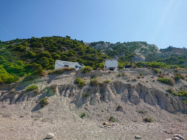 kavicsos magasparton állnak a lakóautók a Gialos Beachen, Lefkada, Görögország