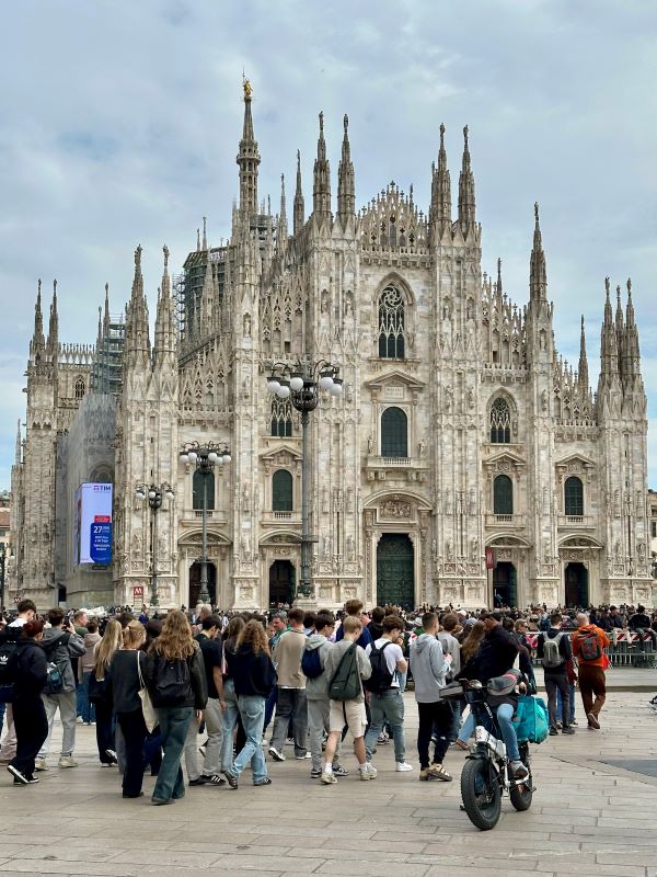 A Milánói Dóm homlokzata a téren sétáló turistákkal, Olaszország