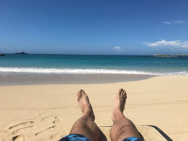 Lábak a homokban a türkiz tenger előtt, Sint Maarten, Karib-tenger